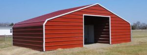 Classic red metal barn with exterior walls enclosed and wide entrance.