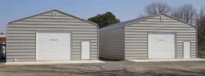 Two identical enclosures with garage door and walk door built on concrete slabs.